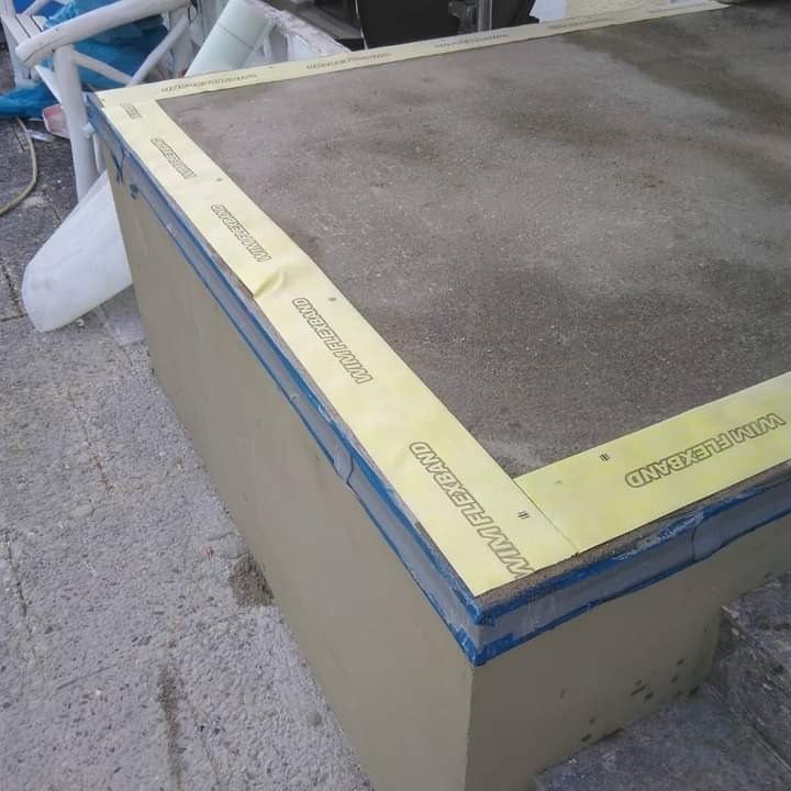 Przygotowanie podłoża pod płytki: izolacja przeciwwodna narożnika z użyciem taśmy WIM FLEXBAND, widoczne łączenie ścian i podłogi, surowy beton w tle.