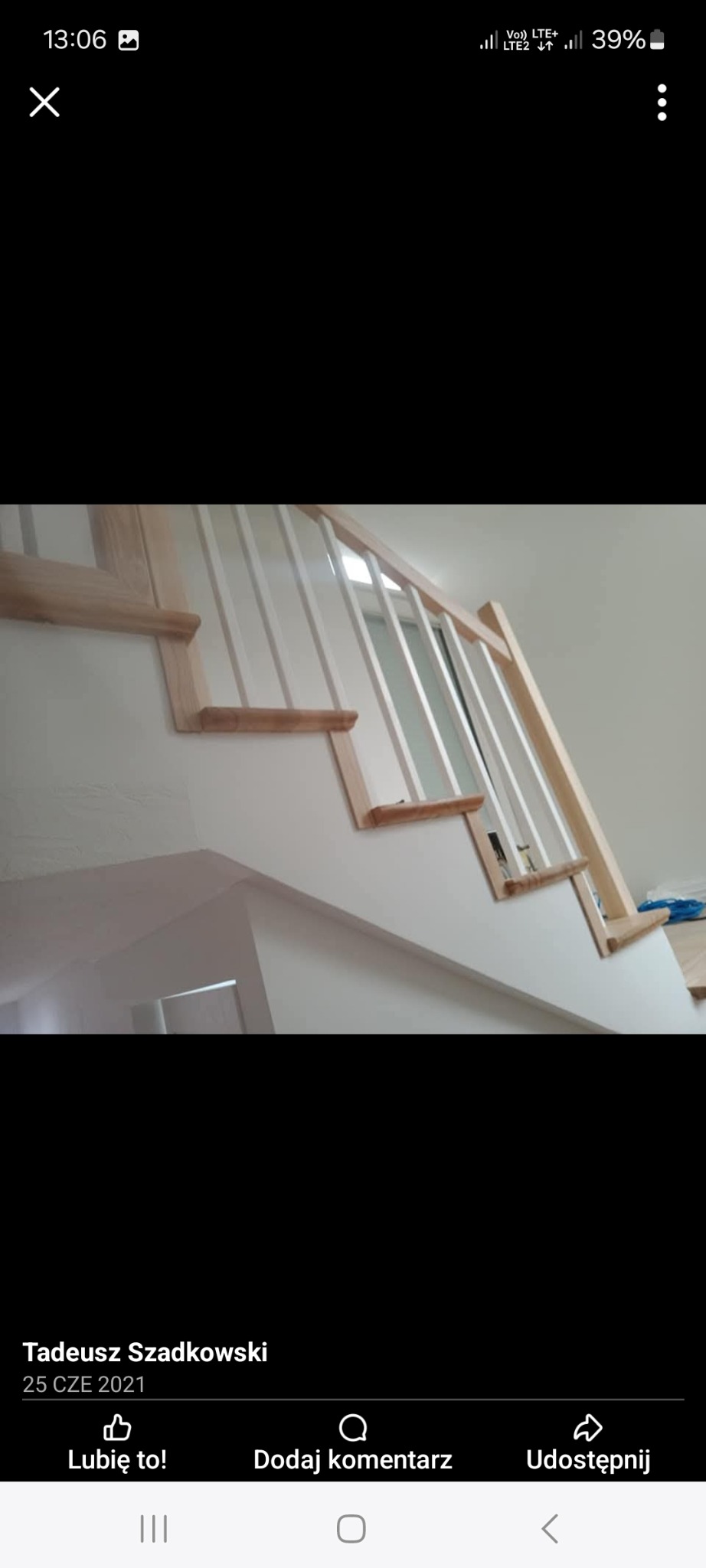 Drewniane schody z białymi balustradami w trakcie montażu, widok od dołu, surowe drewno kontrastuje z bielą ścian.