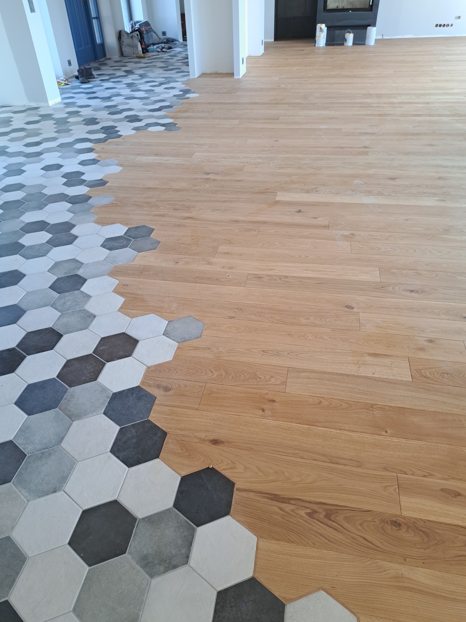 Połączenie drewnianej podłogi z szarymi heksagonalnymi płytkami w nowym wnętrzu.