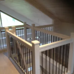 Jasna drewniana balustrada z czarnymi, metalowymi prętami, zabezpieczająca antresolę w domu z drewnianym sufitem i oknem dachowym.