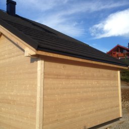 FIRMA STOLARSKO-CIESIELSKA PIOTR KUBIK - Nowoczesna, jasna altana z drewna z czarnym dachem i kominem na tle błękitnego nieba z chmurami.