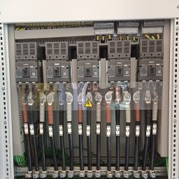 Dziurzyński Kacper G4 free Energy - Rozdzielnia elektryczna z zabezpieczeniami Nader, okablowaniem oznaczonym L1, L2, L3 i żółtym symbolem ostrzegawczym wysokiego napięcia na przezroczystej osłonie.