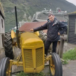 Mężczyzna pozuje obok odrestaurowanego, złotego traktora w scenerii norweskiego fiordu z dużym statkiem wycieczkowym w tle.