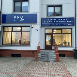 PRO Certyfikowane Biuro Rachunkowe Małgorzata Kugler - Fasada budynku biura rachunkowego z dwoma szyldami: 'PRO' z symbolem strzałki oraz 'CERTYFIKOWANE BIURO RACHUNKOWE' z adresem strony internetowej i numerem telefonu, widok z zewnątrz na wejście...