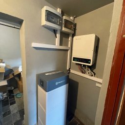 SOLAR ENERGY - Wnętrze pomieszczenia z zamontowanym magazynem energii Pylontech, inwerterem Goodwe z diodami LED oraz dwoma skrzynkami elektrycznymi.