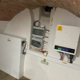 SOLAR ENERGY - Instalacja magazynu energii Encor i inwertera w pomieszczeniu z ceglanym sklepieniem łukowym, widoczne zabezpieczenia elektryczne i narzędzia montażowe.