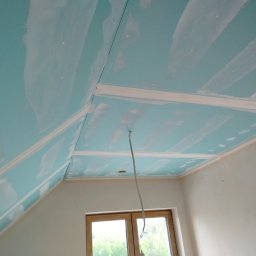 Rafał Aniszewski - Poddasze po montażu płyt karton-gips, widoczne łączenia płyt przygotowane do szpachlowania. W tle okno dachowe i fragment ściany. Widok z dołu.