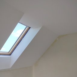 Rafał Aniszewski - Poddasze po szpachlowaniu i malowaniu na biało, widoczne okno dachowe z niebieskim niebem i chmurami. Ściany i sufit gładkie, przygotowane do dalszych prac.