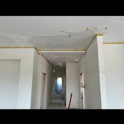 Colorview - Przygotowanie ścian do wykończenia: folia ochronna na suficie, taśma malarska przy krawędziach, surowe ściany w trakcie prac remontowych.