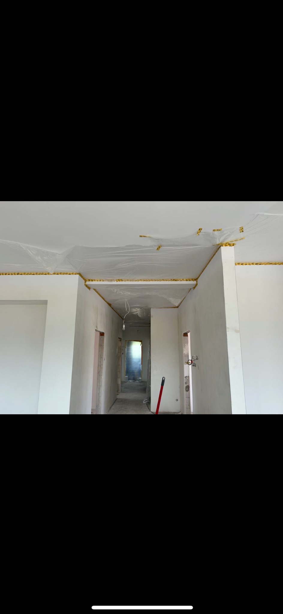 Przygotowanie ścian do wykończenia: folia ochronna na suficie, taśma malarska przy krawędziach, surowe ściany w trakcie prac remontowych.