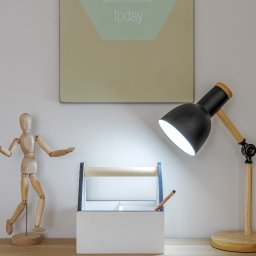 HOME-PLANET Magdalena Rafalska - Drewniany manekin, lampka nocna z drewnianymi elementami, biały organizer z uchwytem i napis 'inspire someone today' na ścianie, tworzą minimalistyczną kompozycję na biurku.
