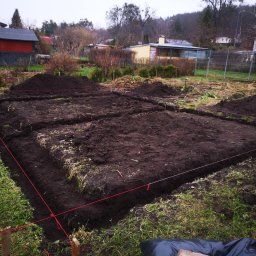 PWMS-BUD SPÓŁKA Z OGRANICZONĄ ODPOWIEDZIALNOŚCIĄ - Wytyczony teren pod budowę z wykopanymi rowami, widoczne sznurki geodezyjne i drewniane paliki, w tle zabudowa jednorodzinna.