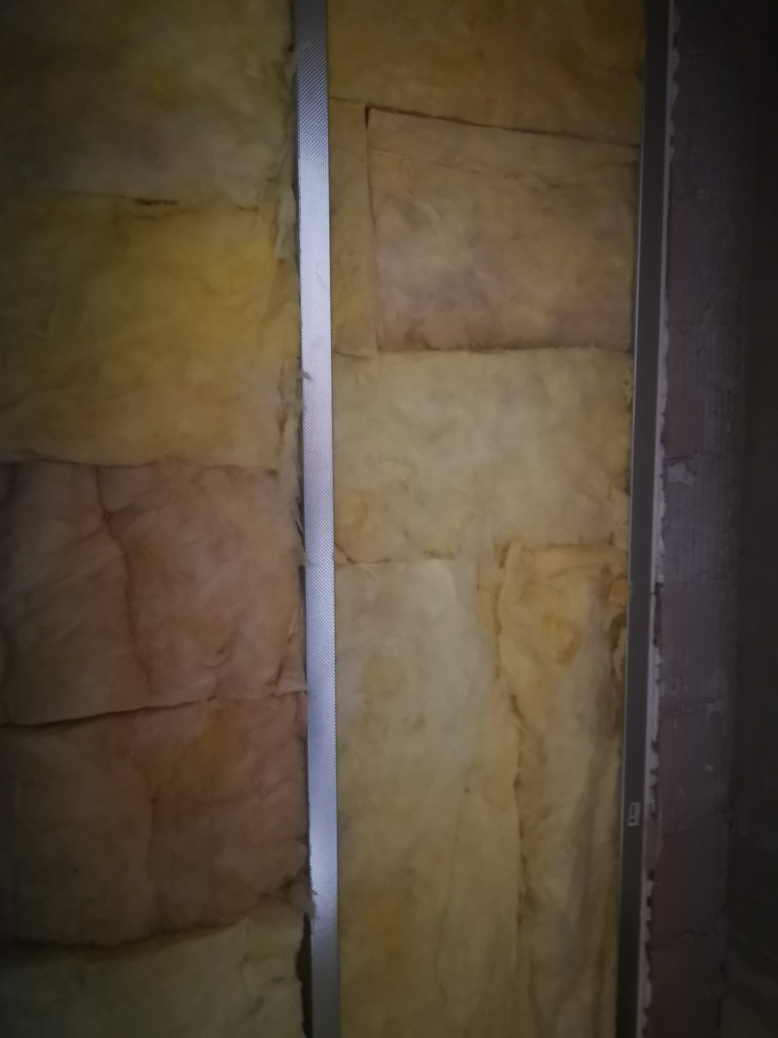 Izolacja z wełny mineralnej zamontowana na ścianie, widoczne metalowe profile konstrukcyjne.