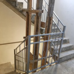 KUNTSTSCHMIEDE BEDNARSKI PIOTR - Wnętrze budynku w trakcie remontu: metalowa balustrada schodowa z drewnianą konstrukcją wsporczą.