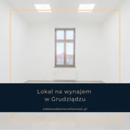 Puste, jasne pomieszczenie z oknem, widok na ceglany budynek przez okno, białe ściany, szara podłoga, grzejnik pod oknem, dwie lampy sufitowe.