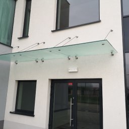 POLER-MET MAREK UDZIK - Szklany daszek nad wejściem do budynku w Czarnkowie, wsparty na metalowych wspornikach, widok z dołu.