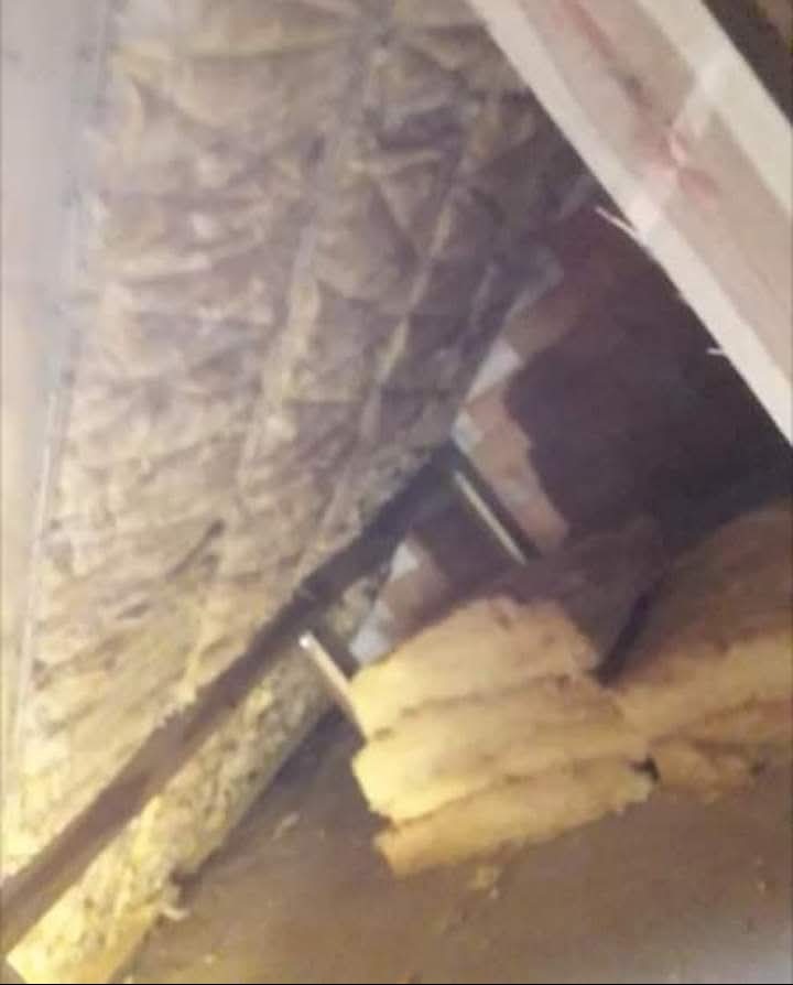 Fragment poddasza w trakcie prac izolacyjnych: widoczne drewniane elementy konstrukcyjne oraz warstwa izolacji termicznej z folią aluminiową, częściowo ułożona, w tle deski szalunkowe.