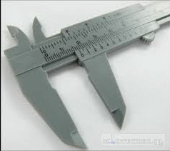 Szary suwmiarka plastikowa, widok z góry pod kątem, skala w milimetrach i calach, na białym tle.