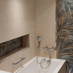 Rem-stan - Nowoczesna łazienka po remoncie: beżowe płytki, wanna z hydromasażem, dekoracyjna ściana z motywem roślinnym, podświetlenie LED pod wanną i wnęka z ozdobnym panelem.