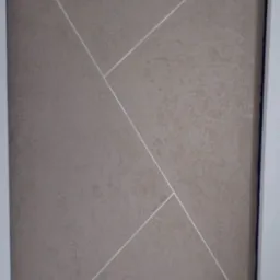 Dekoracyjna ściana z beżową strukturą i białymi, ukośnymi liniami. Widoczna drabina malarska i fragment podłogi. Oryginalne wykończenie wnętrza.