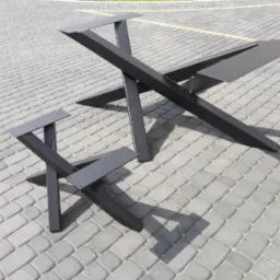 Dwie czarne, metalowe podstawy stołów o geometrycznym kształcie, ustawione na szarej kostce brukowej w słoneczny dzień. Większa podstawa ma kształt litery X z dodatkowymi elementami mocującymi,...