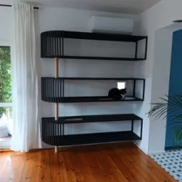 Czarno-drewniany regał na książki i akcesoria dla kota z otworem i przejściem dla zwierząt, na półce siedzi czarno-biały kot.