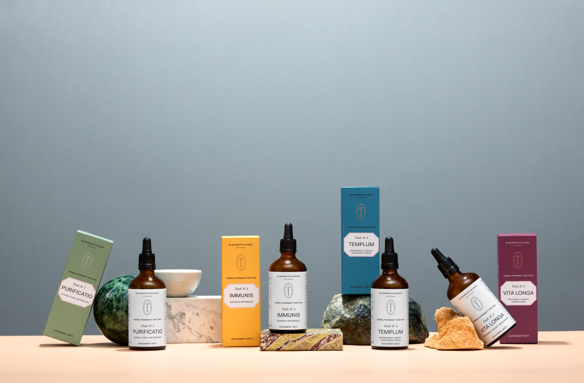 Zdjęcie produktowe Elementa Mundi: Tinct. N°1 Purificatio, N°4 Immunis, N°2 Templum, N°3 Vita Longa. Kompozycja z flakonów, pudełek i naturalnych elementów.