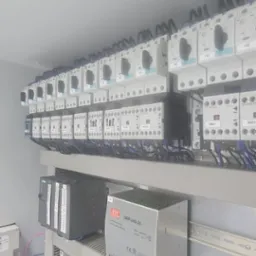 Rozdzielnica elektryczna z zainstalowanymi bezpiecznikami, stycznikami, zasilaczem impulsowym Mean Well DRP-240-24 i modułami sterującymi Siemens, widoczne liczne przewody w kolorze niebieskim...