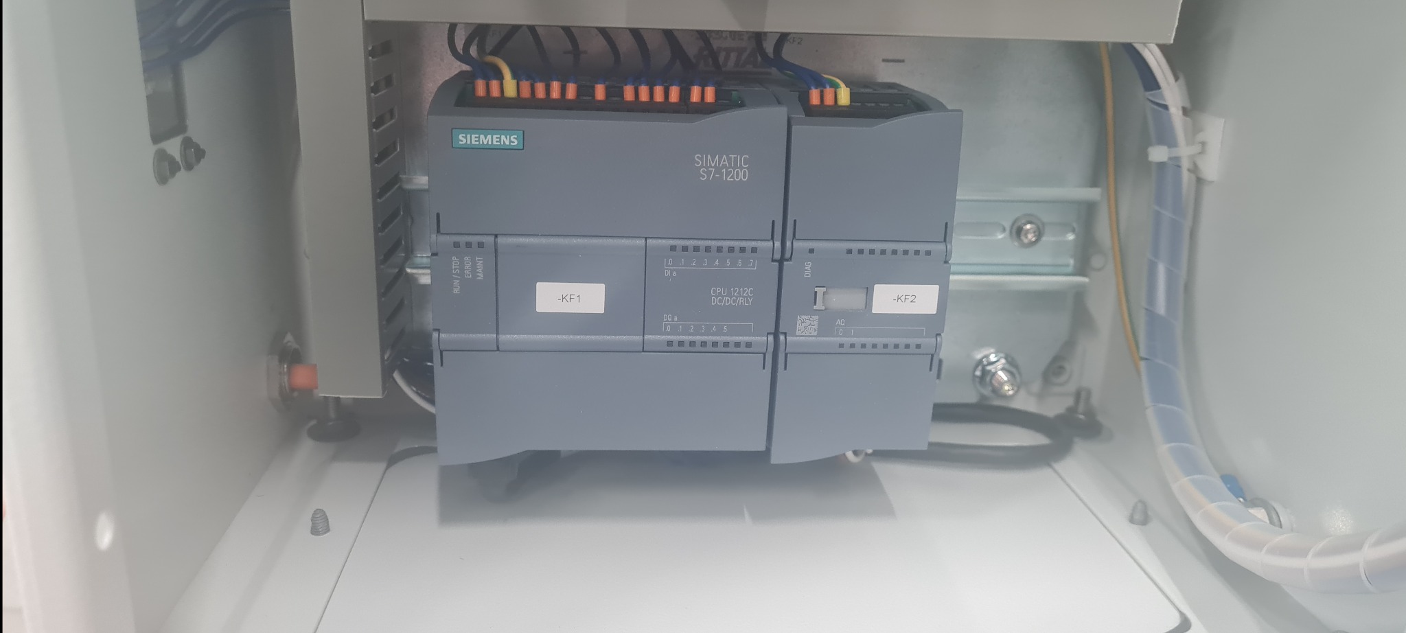 Sterownik PLC Siemens Simatic S7-1200 wewnątrz szafy sterowniczej, widoczne okablowanie i oznaczenia -KF1 oraz -KF2.