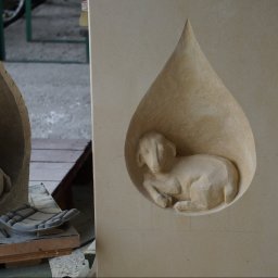 ARCHITEKTURA I RZEŹBA AGNIESZKA WOLSKA-CIELIŃSKA - Ręcznie rzeźbiony w piaskowcu motyw baranka w kształcie łzy, obok druga rzeźba w surowym wykończeniu, dłuta kamieniarskie. Detal pracy kamieniarskiej.