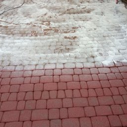 Lavador Łukasz Biazik - Częściowo umyta czerwona kostka brukowa, widoczne ślady czyszczenia pod ciśnieniem, w górnej części brudna woda i resztki zanieczyszczeń.