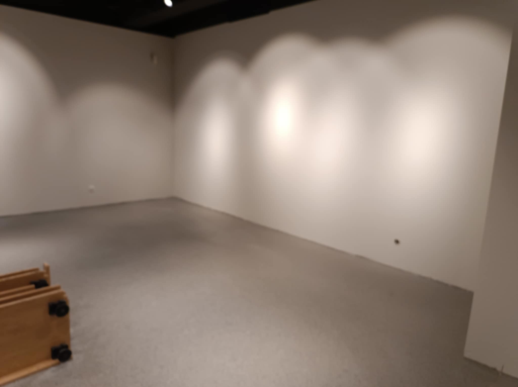 Pusty pokój po pracach przygotowawczych, ściany pomalowane na jasny odcień, widoczne ślady po szpachlowaniu, na podłodze częściowo rozłożone elementy drewniane, prawdopodobnie do montażu mebli.