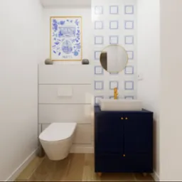 Kompaktowa łazienka z toaletą w zabudowie, umywalką na szafce w kolorze granatowym ze złotymi akcentami, okrągłym lustrem i dekoracyjną grafiką w stylu portugalskim.