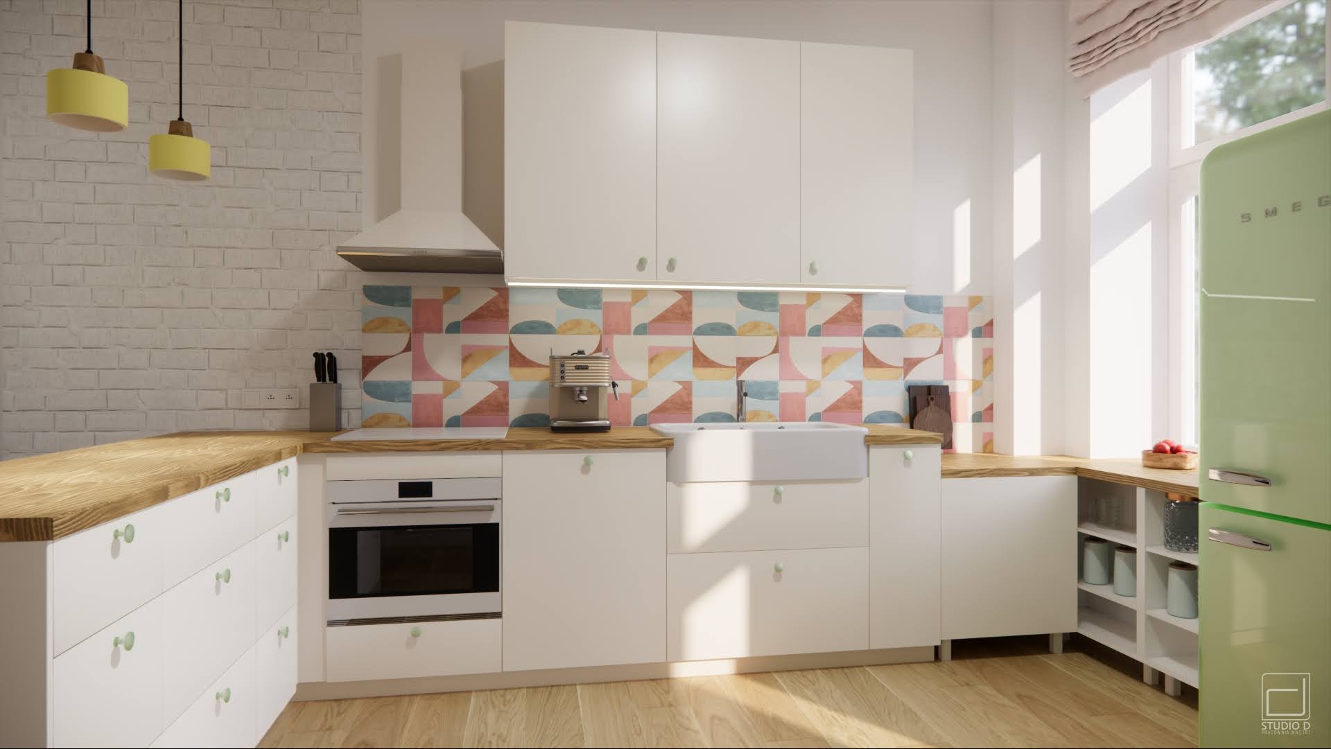 Jasna kuchnia z białymi szafkami, drewnianym blatem, kolorową mozaiką nad blatem i zieloną lodówką Smeg; widoczne żółte lampy wiszące, ekspres do kawy i ceramiczny zlew.