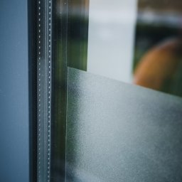 Amadeusz Kośmider Shiny Visions - Detale okna z folią matującą, widoczne listwy i struktura powierzchni szkła.