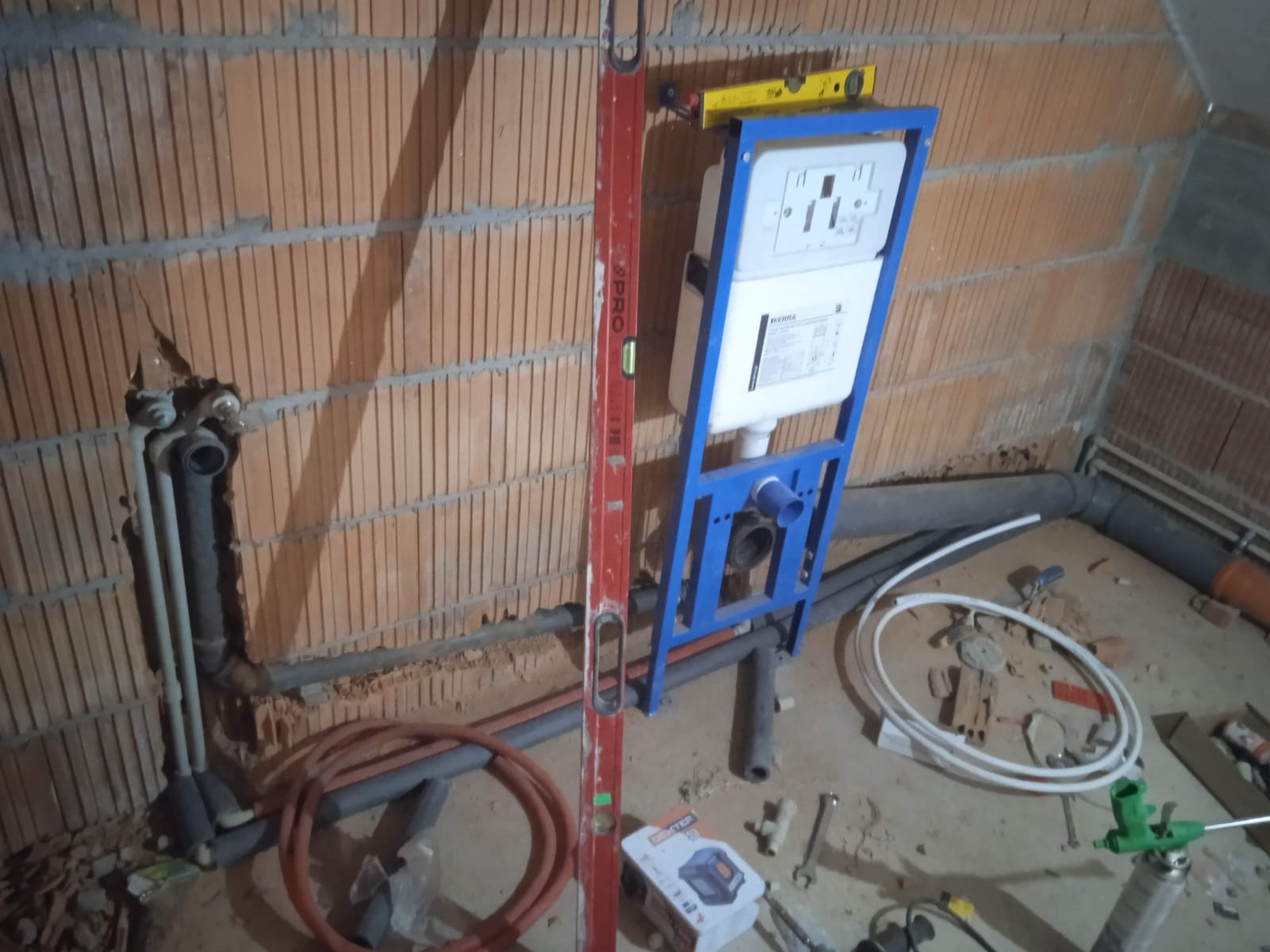 Montaż stelaża podtynkowego WC z instalacją wodno-kanalizacyjną w trakcie prac wykończeniowych w Sieradzu. Widoczny poziomica i narzędzia.