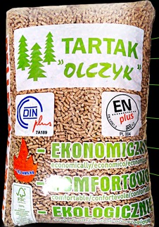 Worek z pelletem drzewnym z widocznym logo producenta 'Tartak Olczyk' oraz certyfikatami DINplus i ENplus. Widoczne zielone choinki w logo i napisy 'Ekonomiczny', 'Komfortowo', 'Ekologiczny'.