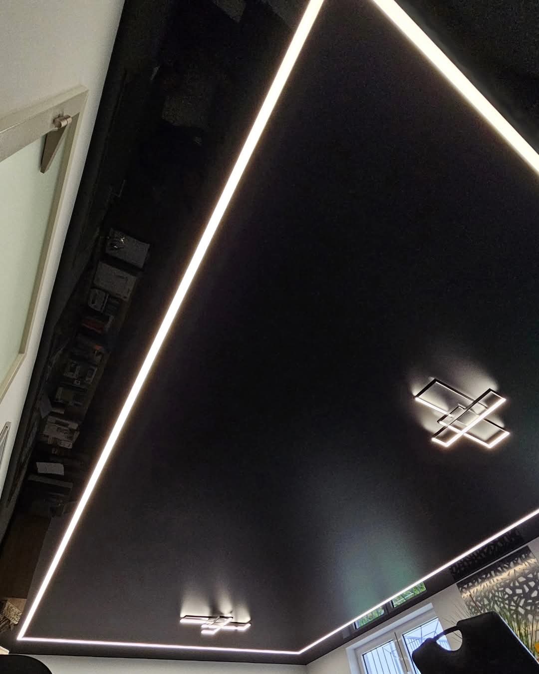 Czarny, lustrzany sufit z oświetleniem LED w kształcie prostokąta i dwoma nowoczesnymi lampami sufitowymi.