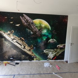 Katarzya Jarosław - Pokój z fototapetą przedstawiającą kosmiczną bitwę, widoczne narzędzia i folia ochronna na podłodze sugerują prace wykończeniowe.
