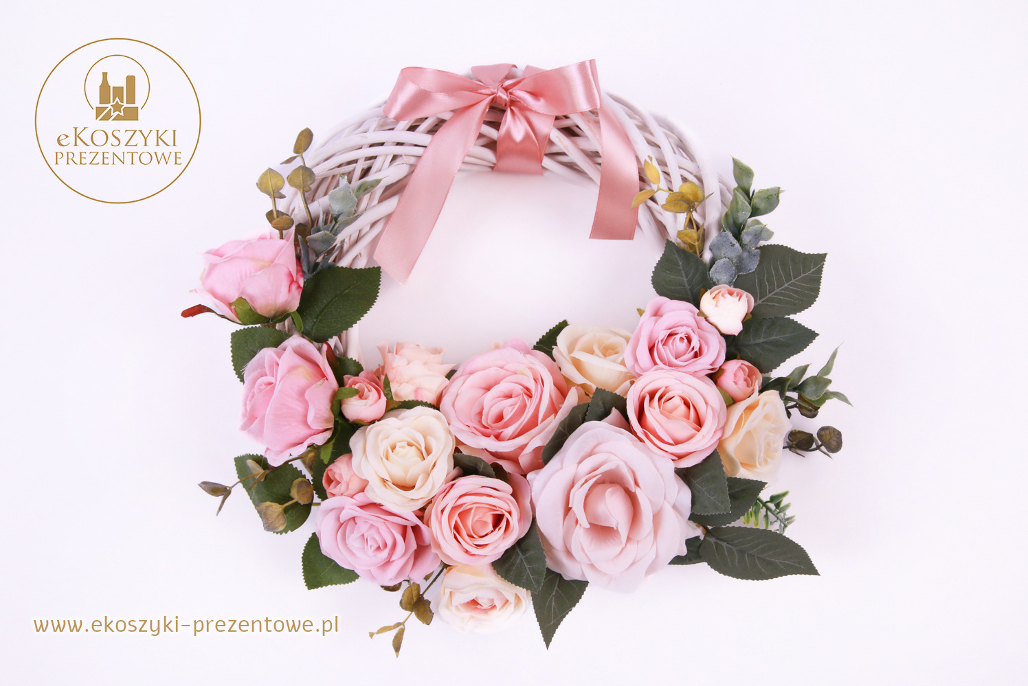 Wieniec dekoracyjny z białej wikliny, ozdobiony pastelowymi różami i satynową kokardą w odcieniach różu, na jasnym tle. Delikatny, romantyczny.
