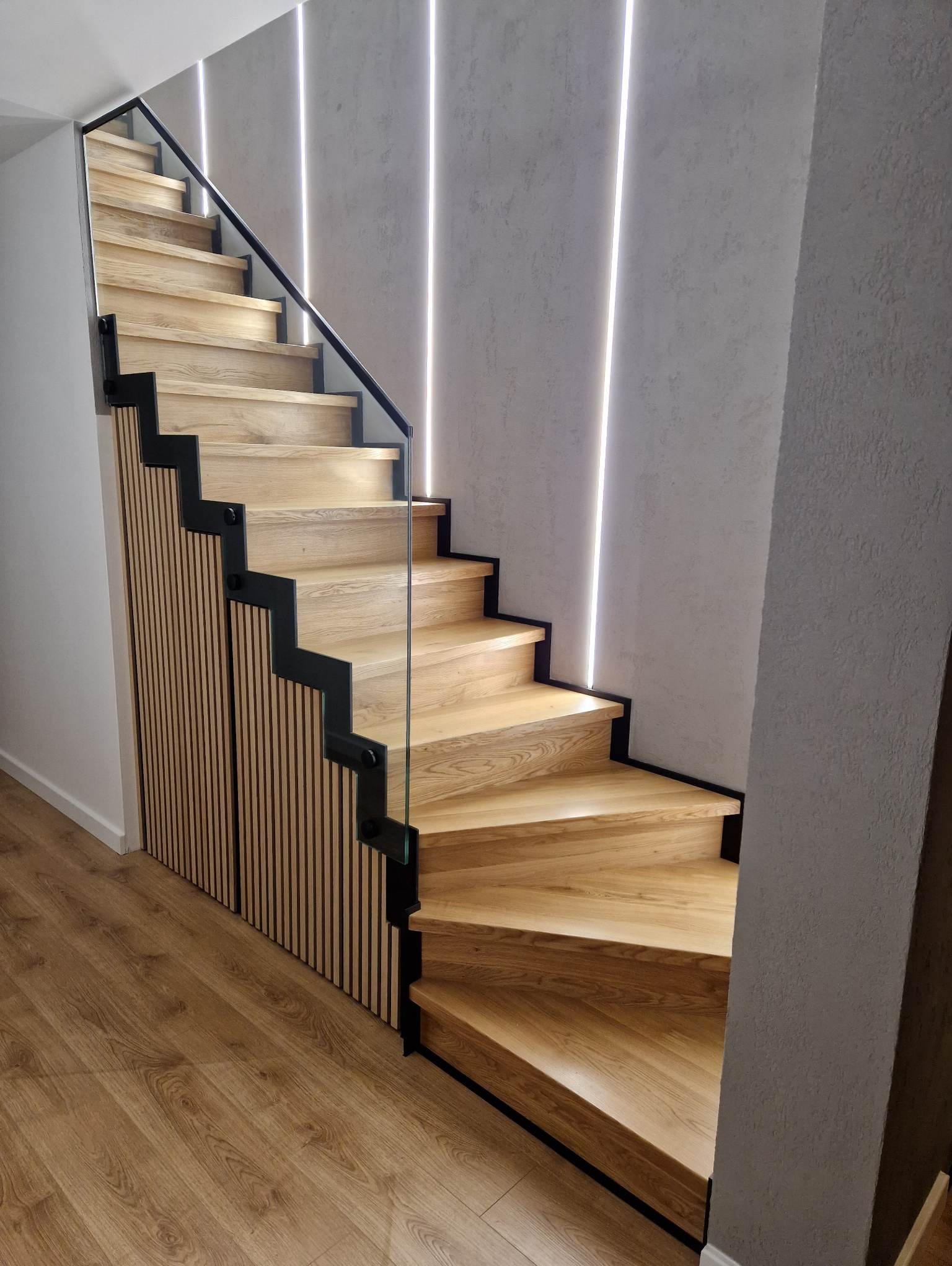 Schody dębowe na konstrukcji metalowej ze szklaną balustradą