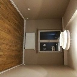 Tesmedia - Wykończone wnętrze pokoju w Aleksandrowie Łódzkim: ściany pomalowane na beżowo, jedna ściana wyłożona panelami imitującymi drewno, biały grzejnik pod oknem, nowoczesna lampa na ścianie.