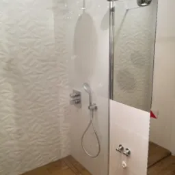 Nowoczesna kabina prysznicowa z deszczownicą, drewnopodobną podłogą i trójwymiarową białą ścianą, oświetlona wiszącymi chromowanymi lampami.