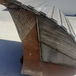 Fragment metalowej konstrukcji z widocznymi spawami, częściowo pokrytej siatką wzmacniającą i oznaczeniem 'HB 400'.