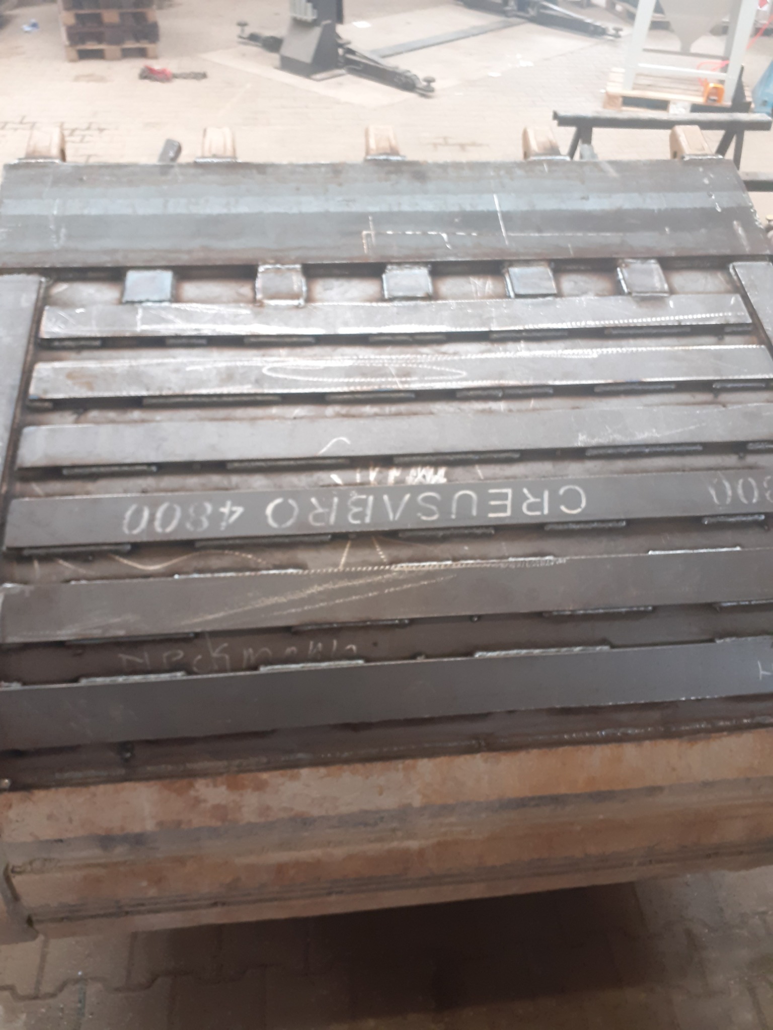 Metalowa konstrukcja z napisem CREUSABRO 4800, spawana z wielu elementów, widoczne ślady po spawaniu i obróbce, w tle warsztat.