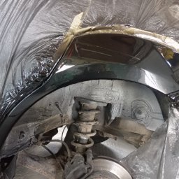 Bilard Garage - Zabezpieczone nadkole auta po nałożeniu warstwy ochronnej, widoczna sprężyna zawieszenia i elementy układu hamulcowego. Prace blacharsko-lakiernicze w toku.