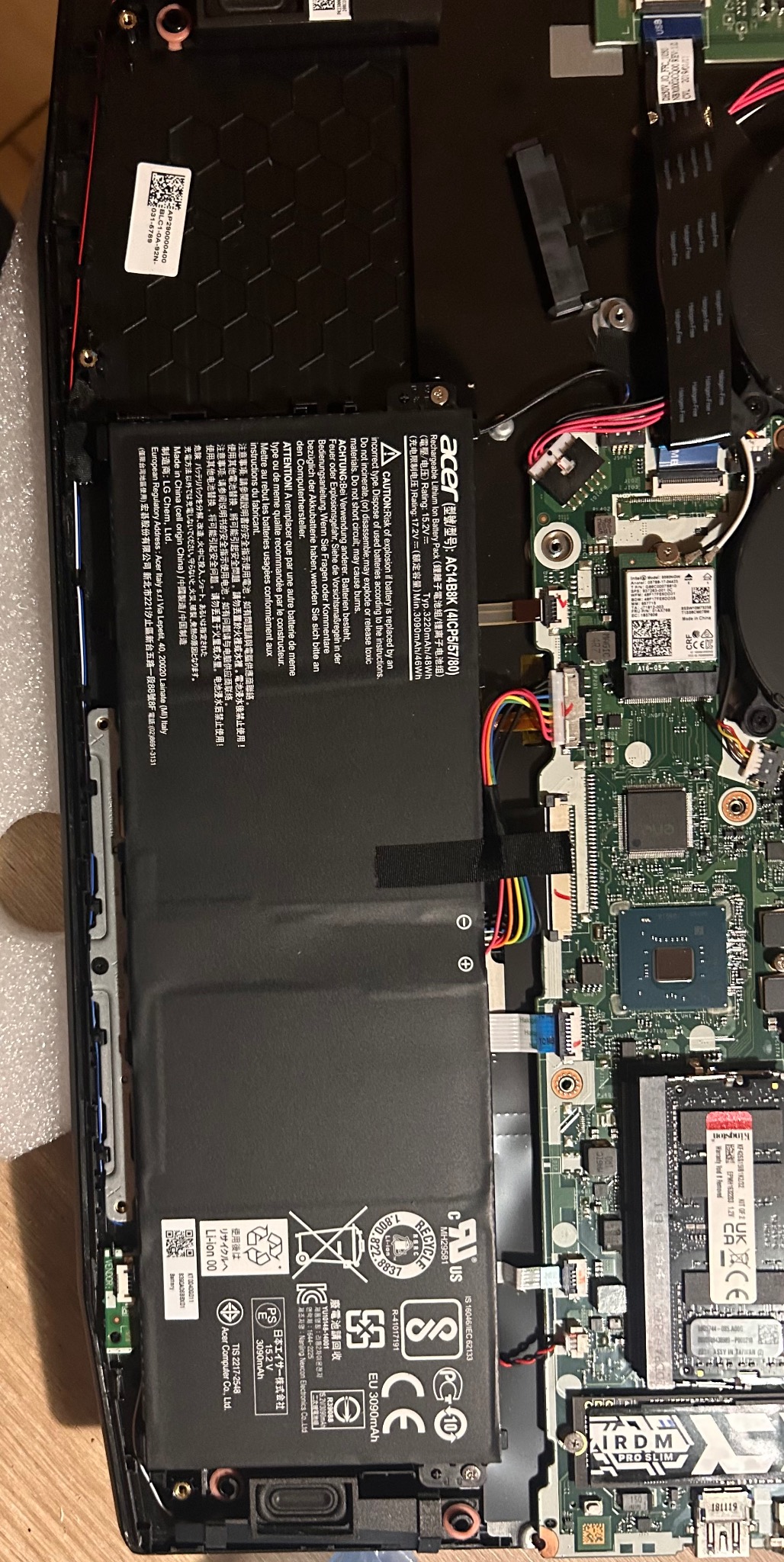 Wnętrze laptopa Acer z widoczną baterią, płytą główną i elementami układu chłodzenia po konserwacji, z bliska. Widoczne oznaczenia i komponenty.