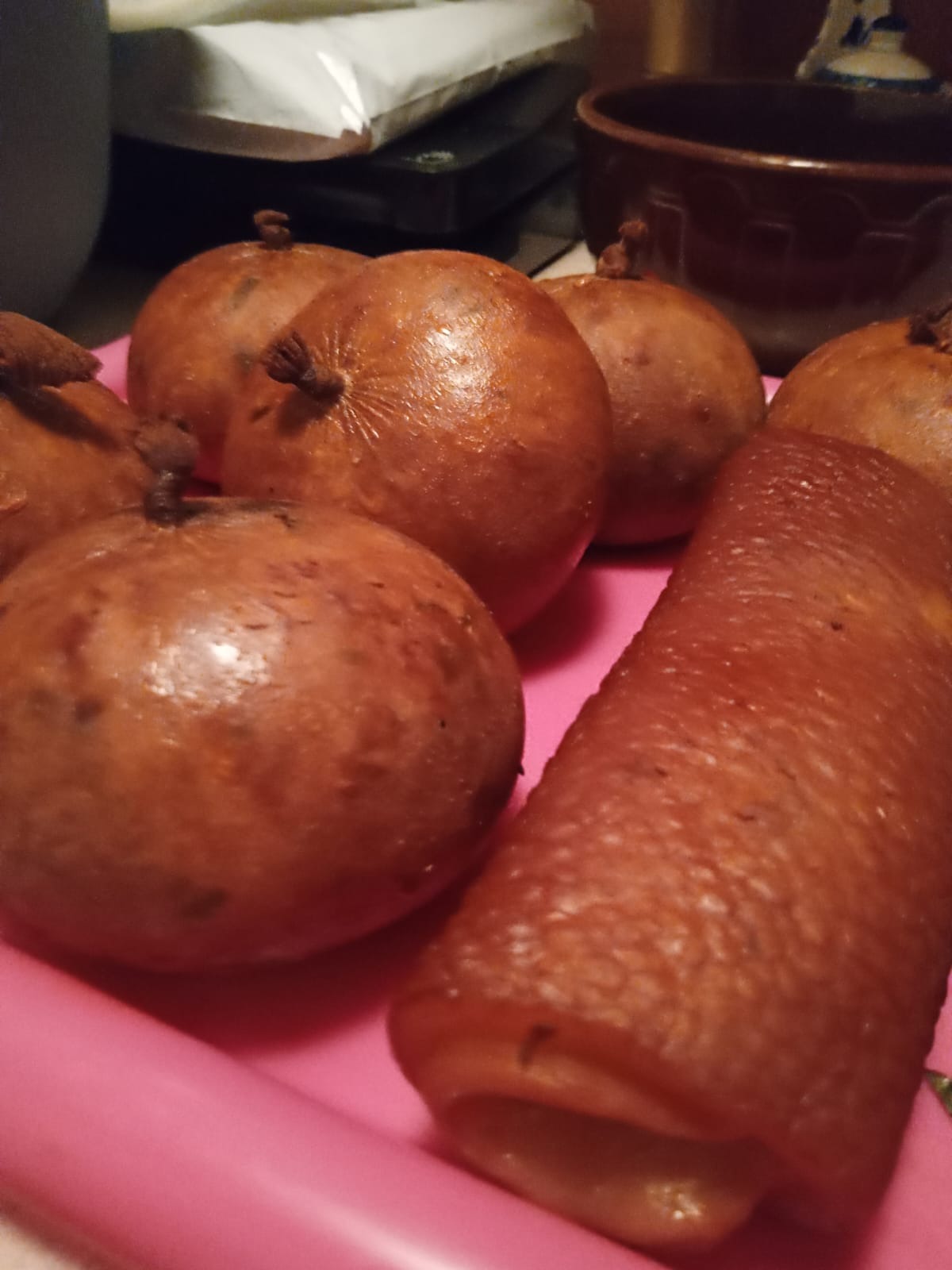 Kaszanka w jelicie naturalnym, ułożona na różowej tacy, widoczne brązowe naczynie w tle.