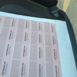 VIARTMEDIA MONIKA MINORCZYK - Stos arkuszy z naklejkami 'Organizer na podkłady' leżący na siedzeniu samochodu, widok z góry.