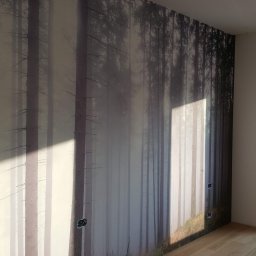 Pro-Bud Krzysztof Kargut - Pokój z fototapetą przedstawiającą mglisty las i parkietem, widoczne niedokończone gniazdka elektryczne na ścianie i wystające kable ze ściany.